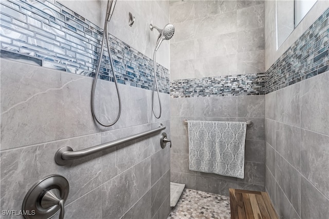 bathroom with a tile shower and tile walls