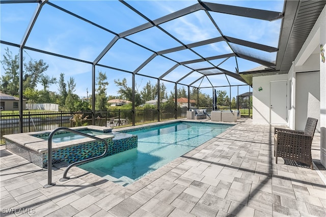 view of pool with an in ground hot tub, a water view, glass enclosure, and a patio