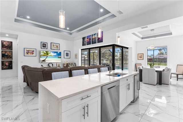 kitchen with an island with sink, dishwasher, a raised ceiling, and white cabinetry