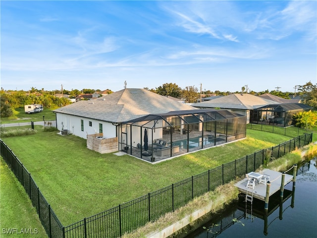 rear view of property with a water view, a patio, a fenced in pool, a lawn, and a lanai