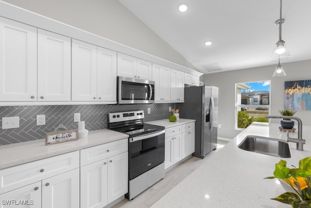 kitchen with tasteful backsplash, sink, lofted ceiling, hanging light fixtures, and stainless steel appliances