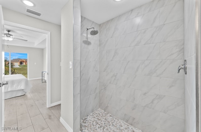 bathroom with ceiling fan and tiled shower