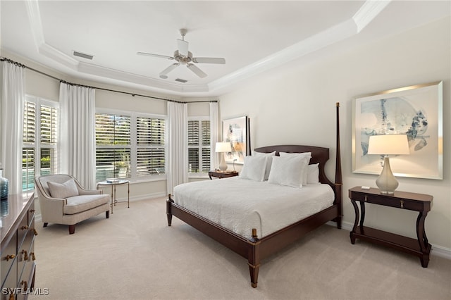 bedroom with light carpet, ornamental molding, a tray ceiling, and ceiling fan