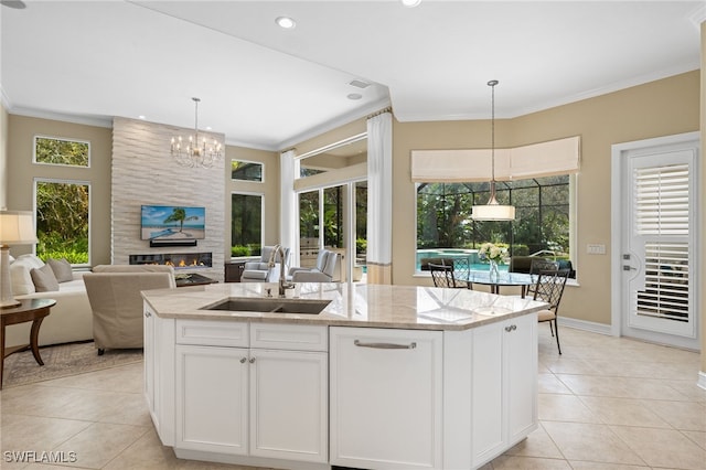 kitchen featuring a center island with sink, sink, white cabinetry, and pendant lighting