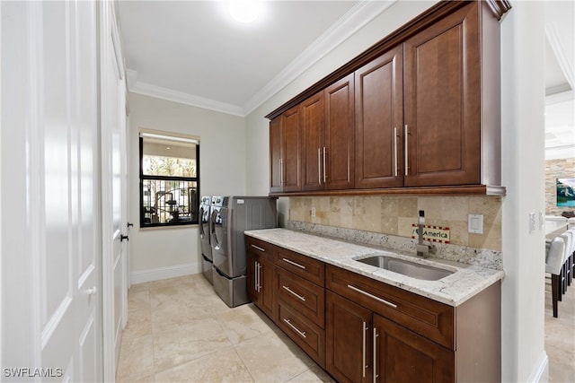 washroom with light tile patterned flooring, washer and dryer, sink, cabinets, and crown molding