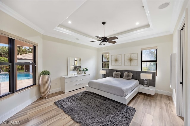 bedroom featuring a tray ceiling, light hardwood / wood-style flooring, and ornamental molding