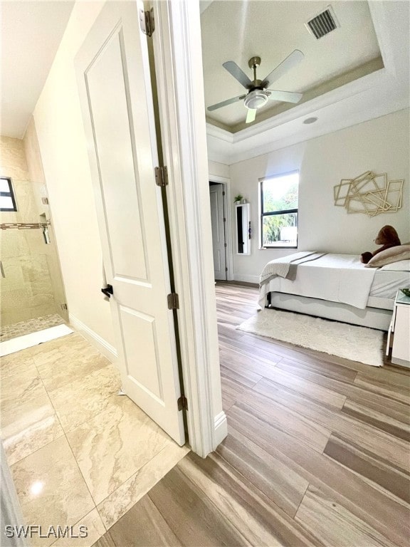 unfurnished bedroom featuring light hardwood / wood-style flooring, a raised ceiling, and ceiling fan