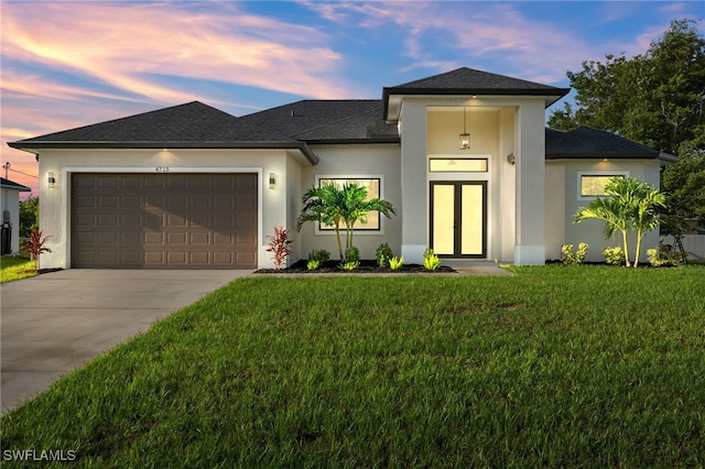 prairie-style house with an attached garage, a yard, driveway, and stucco siding