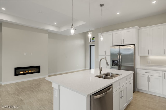 kitchen with sink, an island with sink, white cabinetry, light hardwood / wood-style floors, and stainless steel appliances