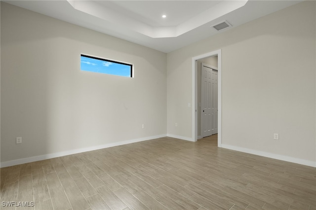 empty room with recessed lighting, a tray ceiling, visible vents, and light wood-style floors
