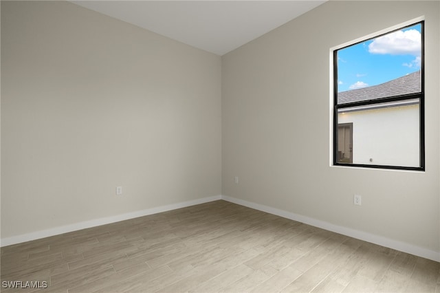 unfurnished room featuring baseboards and light wood-type flooring