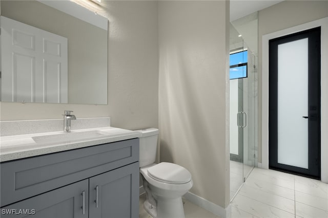 bathroom featuring vanity, toilet, marble finish floor, baseboards, and a stall shower