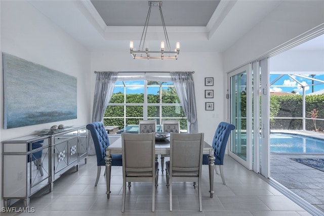 dining area with a chandelier and a raised ceiling