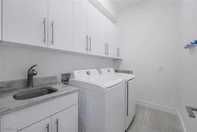 laundry area featuring baseboards, a sink, cabinet space, and washer and dryer