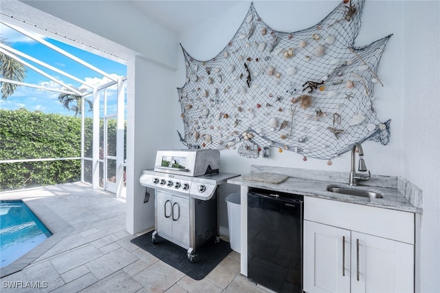 kitchen with light stone counters, refrigerator, stone tile flooring, white cabinetry, and a sink