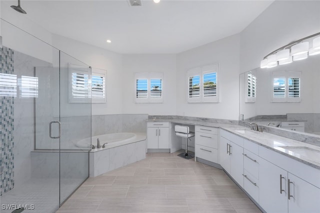 bathroom featuring a stall shower, a garden tub, and vanity