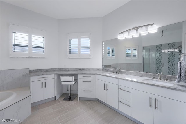 bathroom with healthy amount of natural light, a stall shower, double vanity, and a garden tub