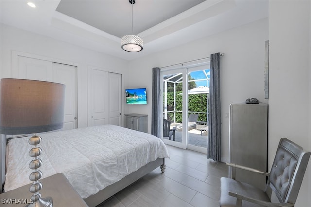 bedroom with access to outside and a raised ceiling