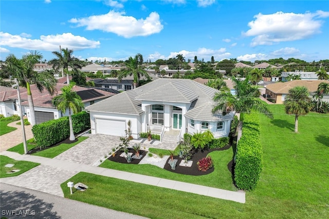 view of front of property with decorative driveway, a garage, a residential view, a front lawn, and a tile roof