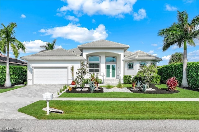 view of front of property featuring a garage, a front yard, decorative driveway, and stucco siding