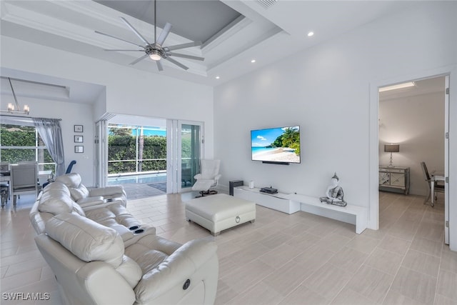living room featuring a high ceiling, recessed lighting, ceiling fan, a chandelier, and a raised ceiling