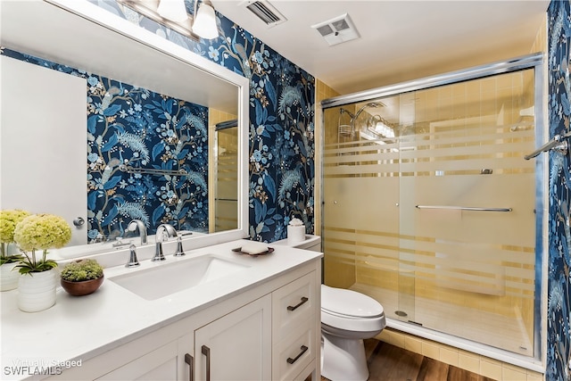 bathroom with hardwood / wood-style flooring, vanity, toilet, and an enclosed shower