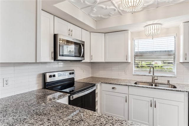 kitchen featuring sink, tasteful backsplash, white cabinetry, stainless steel appliances, and light stone countertops