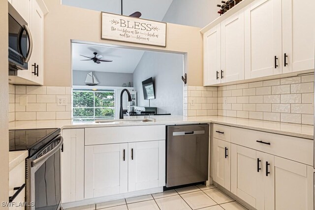 kitchen with lofted ceiling, white cabinetry, stainless steel appliances, and sink