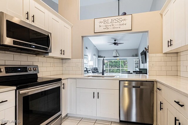 kitchen with a ceiling fan, a sink, white cabinets, appliances with stainless steel finishes, and tasteful backsplash