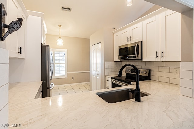 kitchen featuring decorative light fixtures, white cabinetry, appliances with stainless steel finishes, light stone counters, and tasteful backsplash