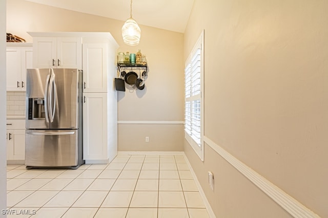 kitchen featuring a wealth of natural light, stainless steel fridge, white cabinets, and vaulted ceiling