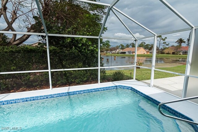 view of swimming pool with a patio, a lanai, and a water view