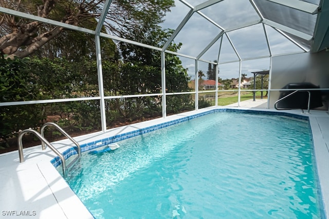 view of pool with area for grilling and glass enclosure