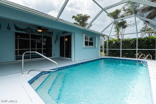 view of swimming pool with a patio, glass enclosure, and ceiling fan