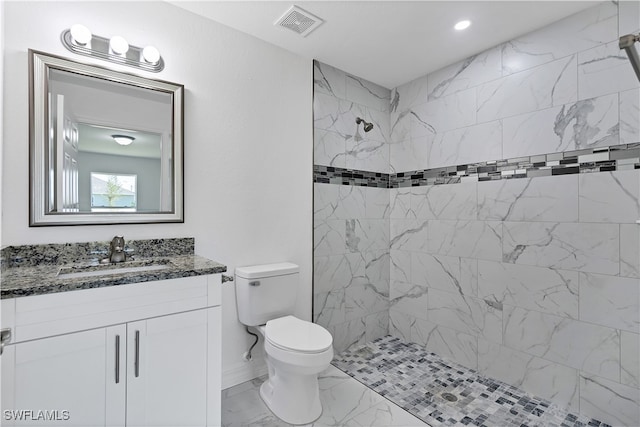 bathroom featuring vanity, toilet, and tiled shower