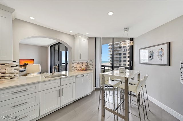 kitchen with white cabinets, white dishwasher, sink, decorative light fixtures, and backsplash