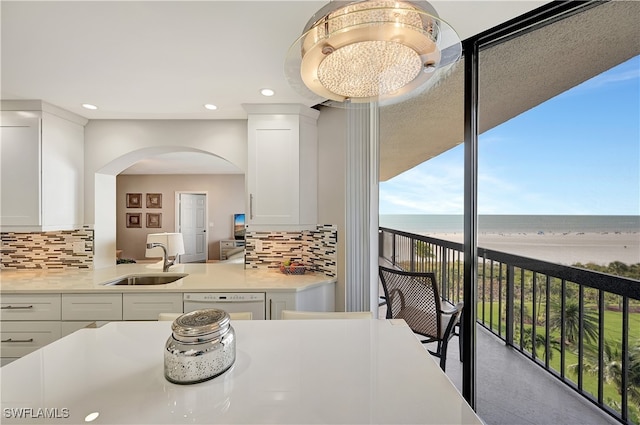 kitchen featuring decorative backsplash, a water view, white cabinetry, and sink