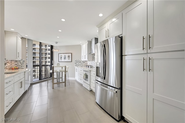 kitchen with tasteful backsplash, wall chimney range hood, white cabinetry, stainless steel refrigerator with ice dispenser, and white range with electric stovetop