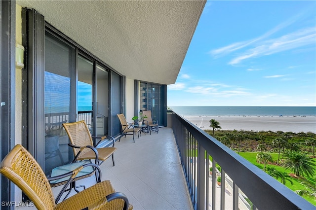 balcony featuring a water view and a beach view