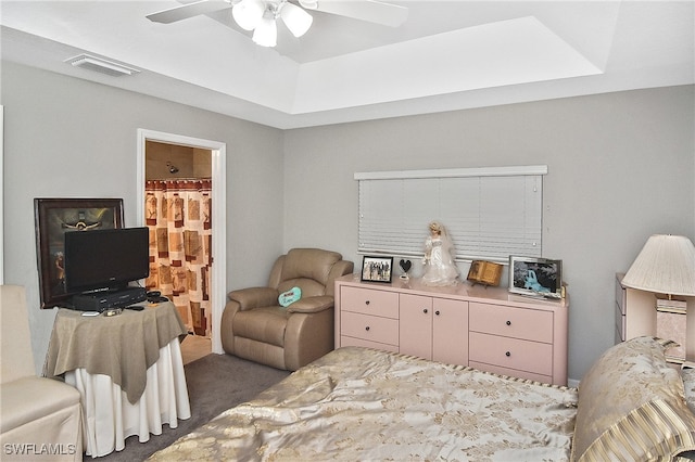 carpeted bedroom with ensuite bath, a tray ceiling, and ceiling fan