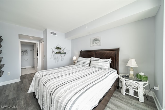 bedroom featuring ensuite bath and wood-type flooring