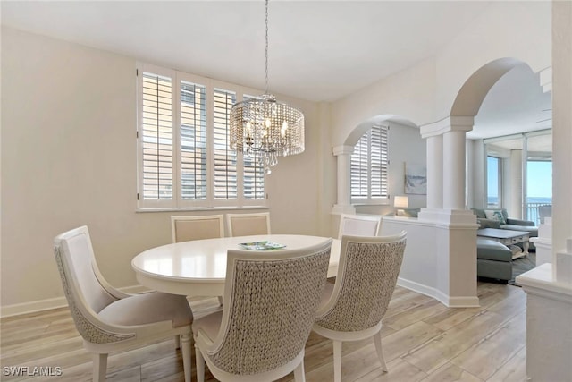 dining area featuring an inviting chandelier, light hardwood / wood-style flooring, and ornate columns