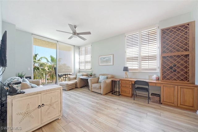 office space featuring ceiling fan, built in desk, and light hardwood / wood-style floors