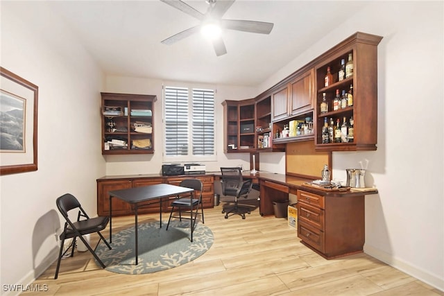 home office featuring light hardwood / wood-style flooring, built in desk, and ceiling fan