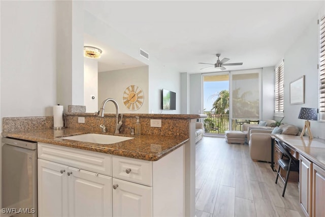 kitchen with dark stone counters, sink, white cabinets, light hardwood / wood-style flooring, and stainless steel dishwasher