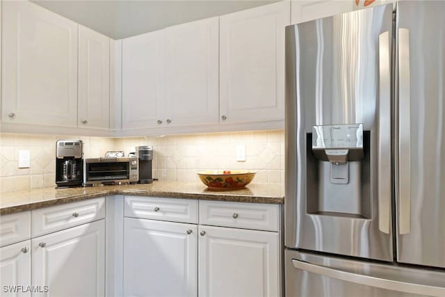 kitchen featuring stainless steel fridge, white cabinetry, light stone counters, and tasteful backsplash