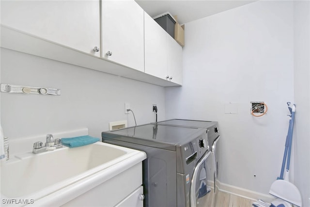 clothes washing area featuring cabinets, light hardwood / wood-style floors, sink, and independent washer and dryer