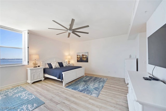 bedroom with ceiling fan, light hardwood / wood-style flooring, and a water view