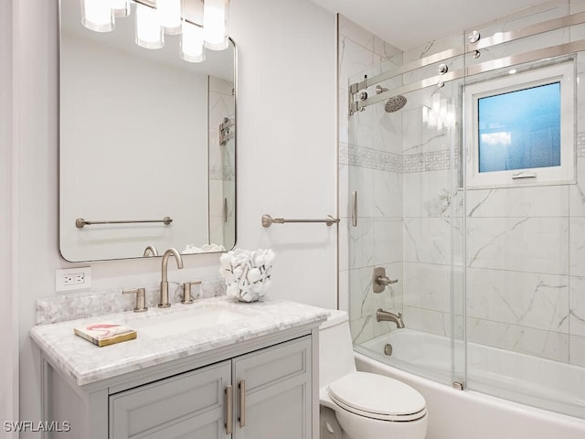 full bathroom with bath / shower combo with glass door, vanity, and toilet