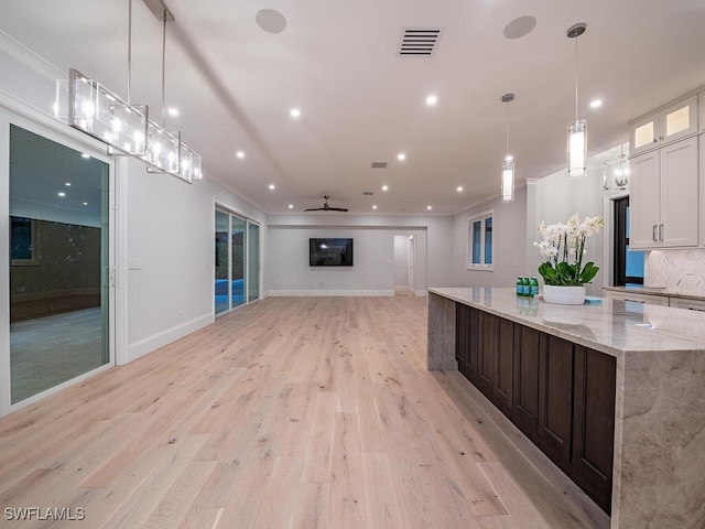 kitchen featuring light hardwood / wood-style flooring, light stone countertops, hanging light fixtures, and white cabinetry